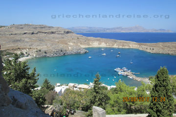 Ansicht der Hafenbucht unterhalb der Akropolis von Lindos auf der Insel rhodos in Griechenland wo ein paar Ausflugsboote vor Anker liegen.