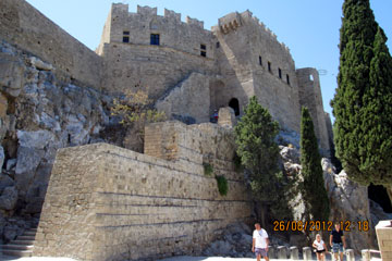 Ansicht der Johanniter Ritterburg bei der Besichtigung von dem Akropolis Berg von Lindos und der Insel Rhodos beim Griechenland Urlaub mit seinem halb runden Turmbau und der Treppe die zum Heiligtum führt.